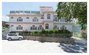 a white house with a car parked in front of it at Hotel Dewanekhas Skardu in Skardu
