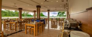 蒙納的住宿－The Lake View Munnar Resort，餐厅设有桌椅和大窗户。