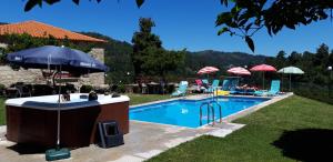 a swimming pool with an umbrella and a hot tub at Casa D`Auleira in Ponte da Barca