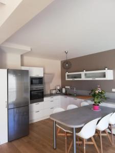 uma cozinha com um frigorífico de aço inoxidável e armários brancos em D5 - Résidence La Montille em Le Mont-Dore