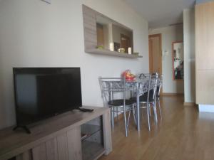a living room with a television and a table with chairs at Apartamento Moncofar playa in Moncófar +8 photos
