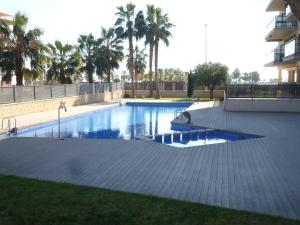 a swimming pool in a yard with palm trees at Apartamento Moncofar playa in Moncófar