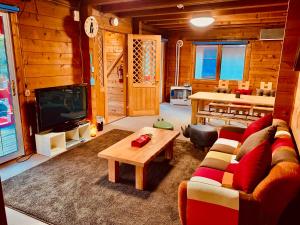 Una sala de estar con un sofá, un televisor y una mesa. en Tomy's Log House - Need CAR, en Shiraoi