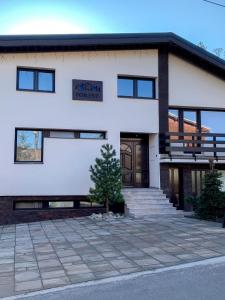 un bâtiment blanc avec un arbre devant lui dans l'établissement Privat FoRest, à Liptovský Mikuláš