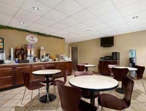 a waiting room with tables and chairs in a restaurant at Super 8 by Wyndham-Tupelo Airport in Tupelo