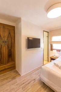 a bedroom with a bed and a flat screen tv on the wall at Anagram Hotel in M&yacute;konos City