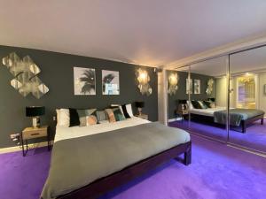 een grote slaapkamer met een groot bed en paars tapijt bij Foley Street Apartments in Londen