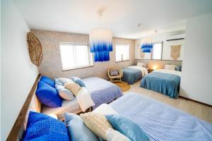 1 dormitorio con 3 camas y almohadas azules en Shisa Terrace Ginoza, en Ginoza