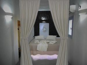 a bedroom with a bed with white curtains at AMO Folegandros in Karavostasi