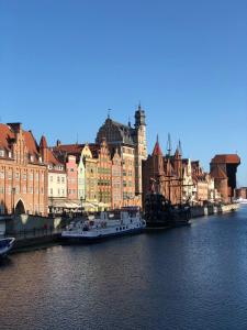 a river with buildings and boats in the water at Willa Biala Lilia Old Town in Gdańsk