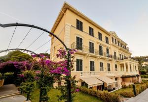 un gran edificio con flores púrpuras delante de él en Diodato Suite Apartment - Amazing Location, WiFi, Pool, Sauna, Gym & Private Garden, en Roquebrune-Cap-Martin