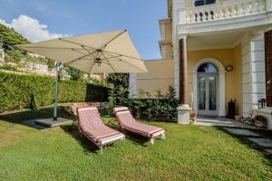 dos sillas y una sombrilla en el patio de una casa en Diodato Suite Apartment - Amazing Location, WiFi, Pool, Sauna, Gym & Private Garden, en Roquebrune-Cap-Martin