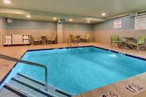 - une piscine dans une chambre d'hôtel avec des chaises et des tables dans l'établissement Holiday Inn Express Pittston - Scranton Airport, an IHG Hotel, à Pittston