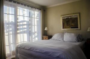 a bedroom with a bed and a large window at Hotel Manoir Atkinson in Valparaíso