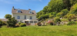 een groot wit huis op een heuvel met een tuin bij Eastwrey Barton Country House in Lustleigh