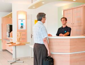 Genshagen的住宿－柏林艮沙宜必思快捷酒店，两个男人站在药房的柜台