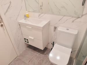 ein weißes Bad mit einem WC und einem Waschbecken in der Unterkunft BairroSweethome in Lissabon