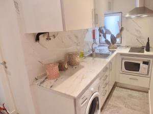 uma cozinha branca com um lavatório e uma máquina de lavar louça em BairroSweethome em Lisboa