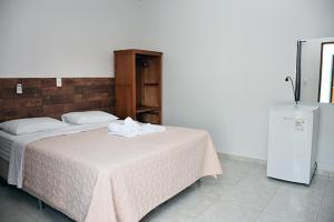 1 dormitorio con 2 camas y nevera en Pousada Estrela Guia en Pirenópolis