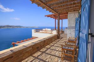 a house with a deck with chairs and the ocean at Antiparos Vibes in Agios Georgios