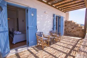 a patio with chairs and a table and a bed at Antiparos Vibes in Agios Georgios