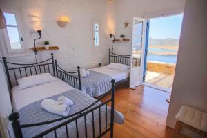two beds in a room with a view of the ocean at Antiparos Vibes in Agios Georgios
