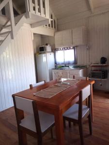 cocina con mesa de madera con sillas y nevera en Las Huellas Cabaña, en Balneario Pehuén-Có