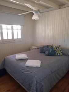 1 dormitorio con 1 cama con 2 almohadas y ventilador de techo en Las Huellas Cabaña, en Balneario Pehuén-Có