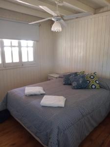 1 dormitorio con 1 cama con 2 almohadas y ventilador de techo en Las Huellas Cabaña en 