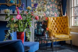 a living room with a yellow chair and vases of flowers at Hotel des Arts in Amsterdam
