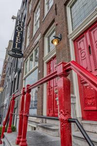 a red building with a red door on a street at Hotel des Arts in Amsterdam