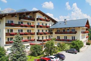 un grande edificio con auto parcheggiate in un parcheggio di Hotel Post a Ramsau am Dachstein