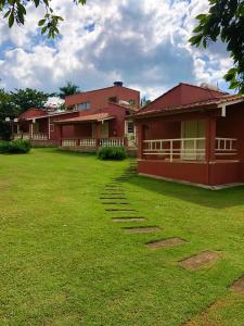 uma casa vermelha com um relvado à frente em Pousada Pontal do Lago em Carmo do Rio Claro