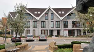 un grande edificio con auto parcheggiate di fronte di Residentie Rivella a Koksijde