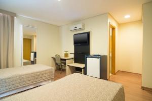 a hotel room with two beds and a table and a desk at Hotel Financial in Belo Horizonte