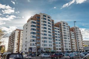 a large white building with cars parked in a parking lot at Luxury Apartments Newton by GLAM in Iaşi