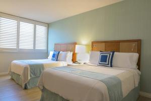 Cette chambre d'hôtel comprend 2 lits bleus et blancs. dans l'établissement Gateway Hotel Santa Monica, à Los Angeles