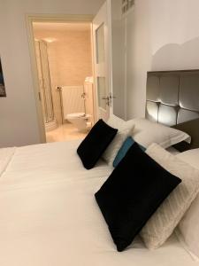 a bedroom with a large white bed with black pillows at Harlingen Garden Apartment in Midlum