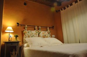 1 dormitorio con cama, lámpara y ventana en Casa rural La Piedrapipa, en Madrigal de la Vera