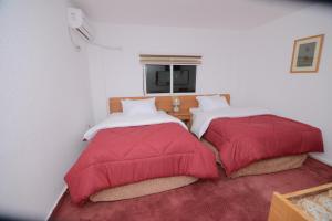 two beds in a room with red and white pillows at Petra Lion Hotel in Wadi Musa