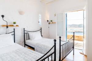 two beds in a room with a view of the ocean at Antiparos Vibes in Agios Georgios