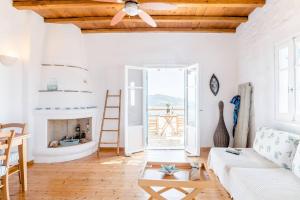 a living room with a ceiling fan and a fireplace at Antiparos Vibes in Agios Georgios