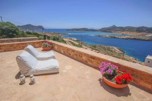 a patio with two white chairs and flowers on a wall at Antiparos Vibes in Agios Georgios