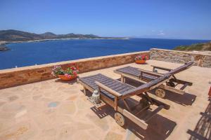 a patio with two chairs and a bench and the ocean at Antiparos Vibes in Agios Georgios