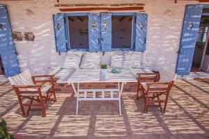 a table and chairs with blue shutters on a patio at Antiparos Vibes in Agios Georgios