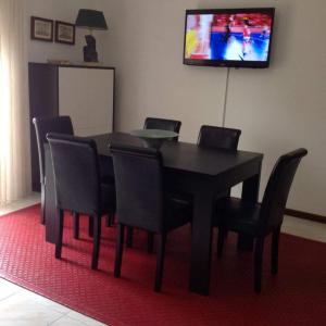 een eettafel met stoelen en een televisie aan de muur bij apartamento Vila do Conde in Vila do Conde