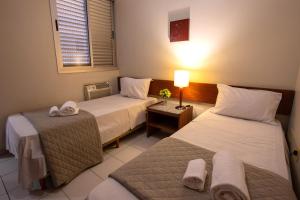 a hotel room with two beds and a lamp at Pampulha Flat in Belo Horizonte +31 photos