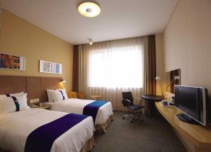 ein Hotelzimmer mit 2 Betten und einem TV in der Unterkunft Holiday Inn Express Panjin Downtown, an IHG Hotel in Panjin