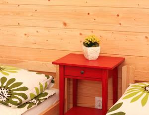 a red table with a plant on it next to a bed at 4 Domki in Sarbinowo
