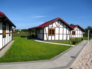 una pequeña casa con un patio de césped al lado de un edificio en 4 Domki en Sarbinowo